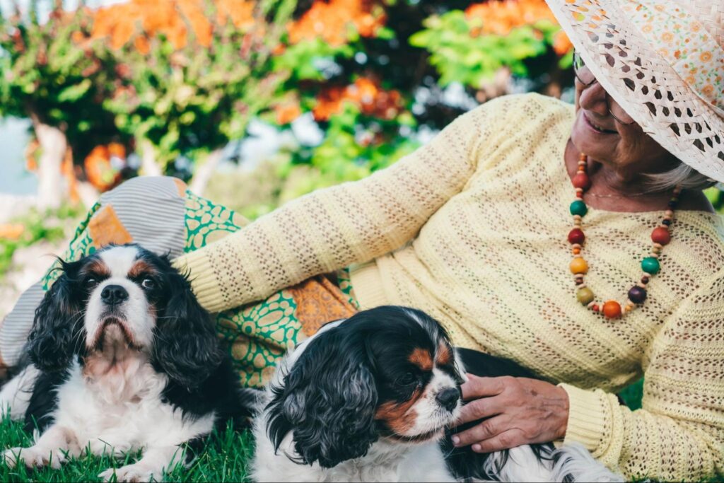 a woman sitting on the grass with two dogs